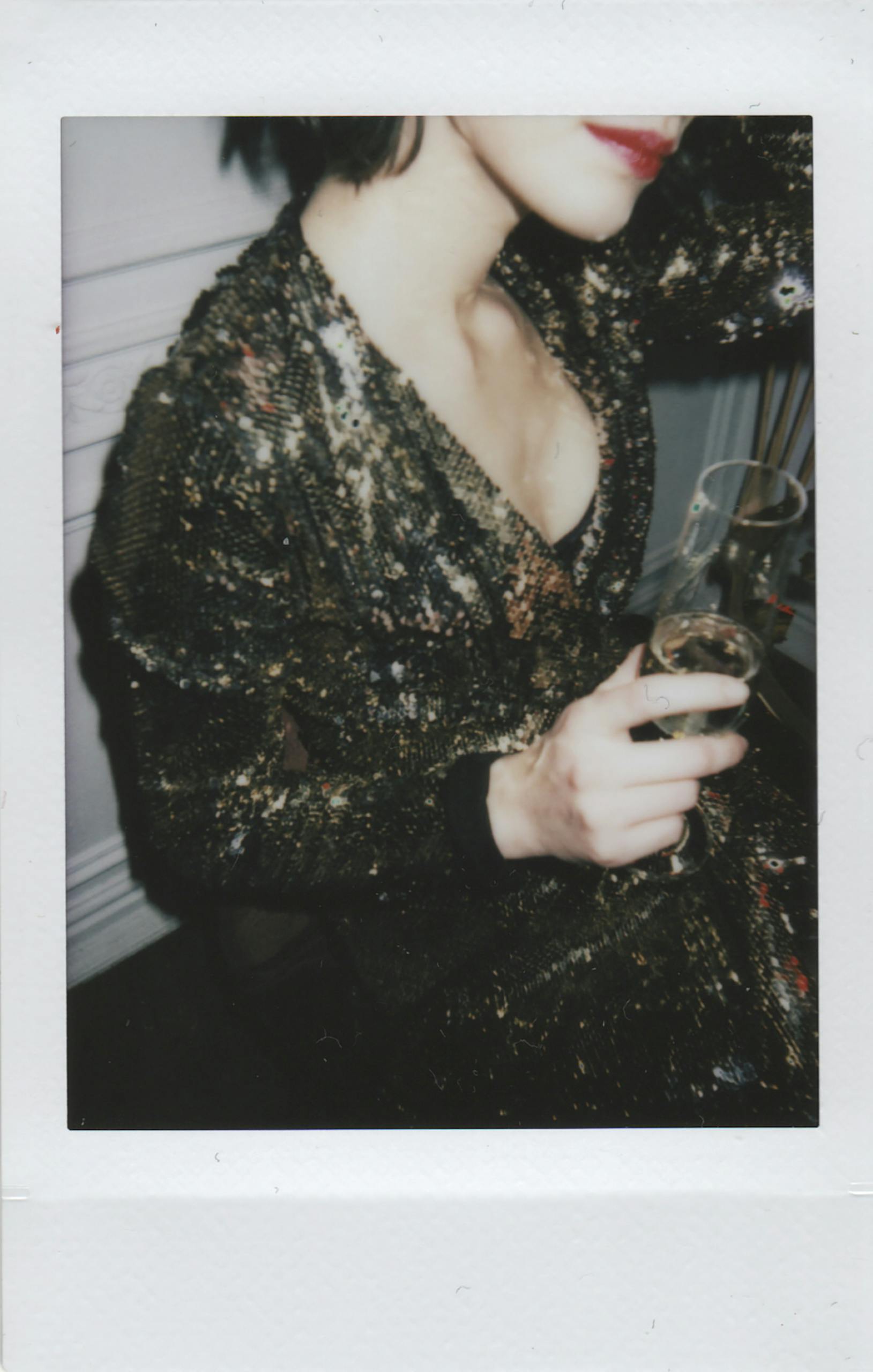 A woman in a sparkly dress holding a champagne glass, exuding glamour.