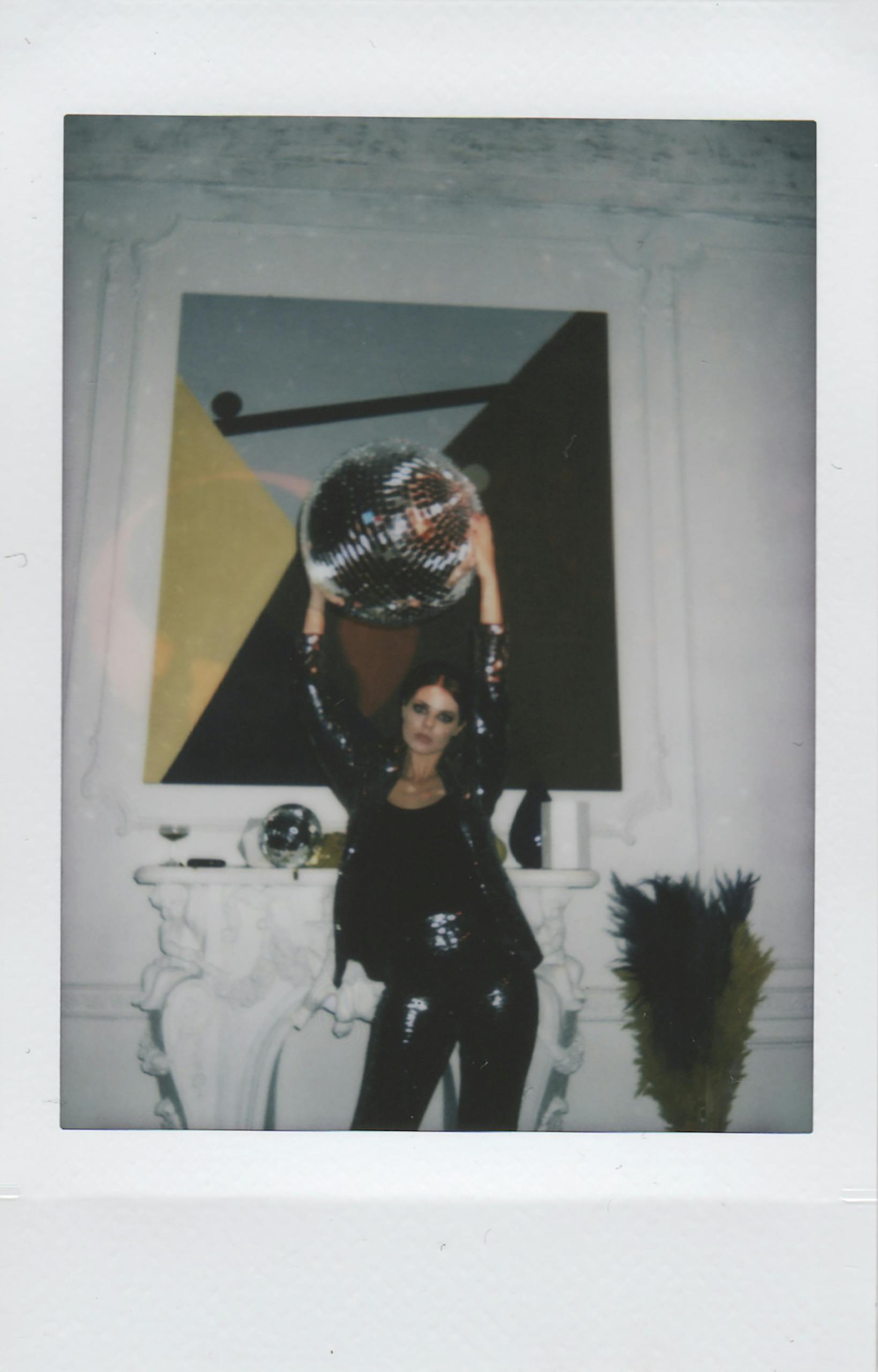 Stylish woman in black holding a disco ball in a chic indoor setting. Perfect for party-themed designs.